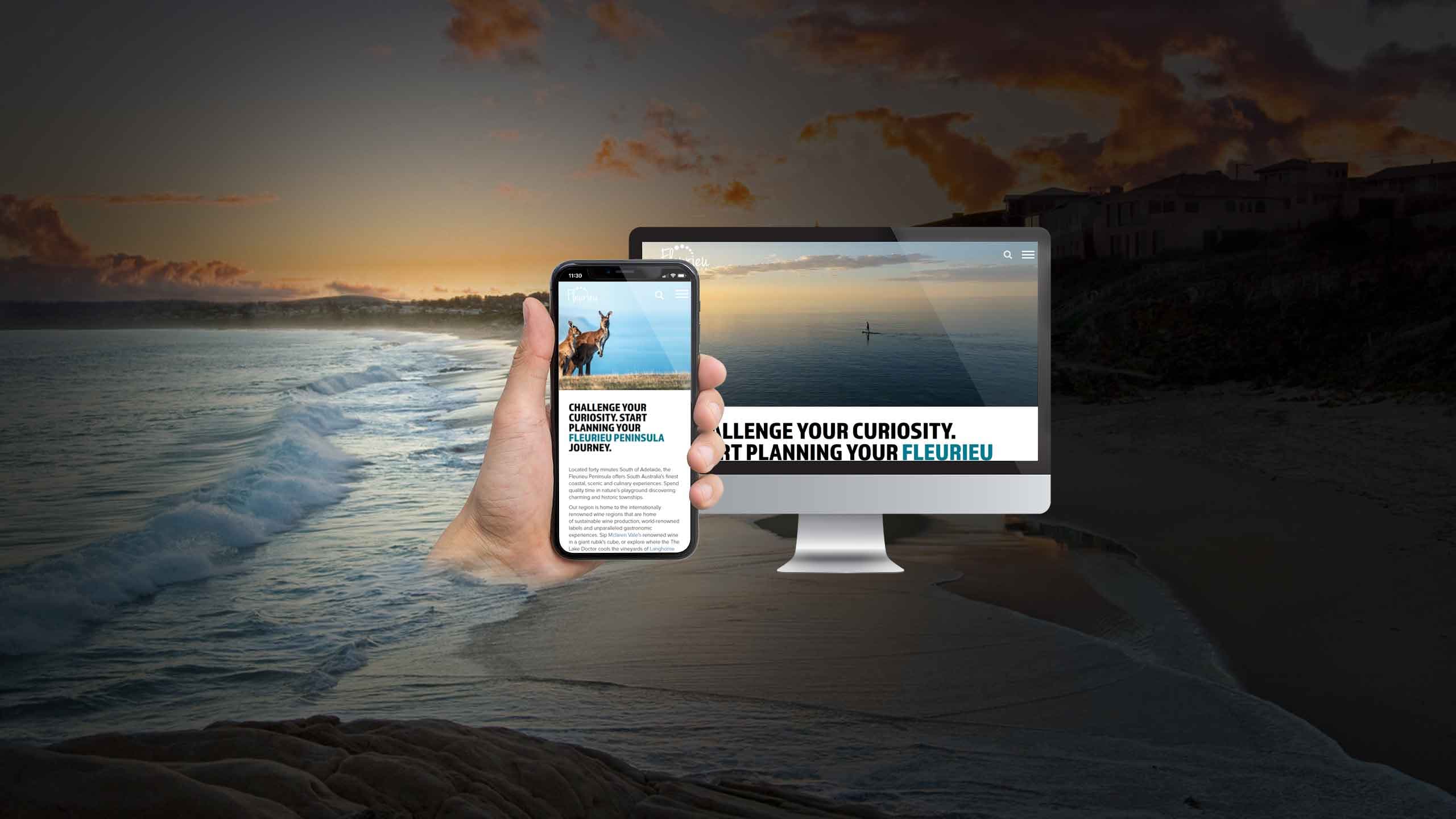 Fleurieu Peninsula Tourism website on a desktop monitor and smartphone over a paddleboarder at sunset