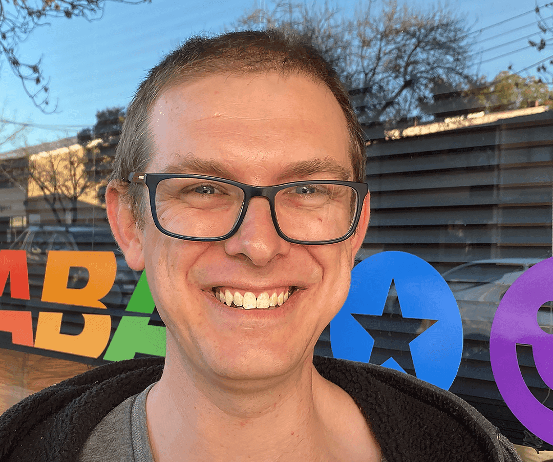 Jack, JABA team member, standing in front of the JABA office signage