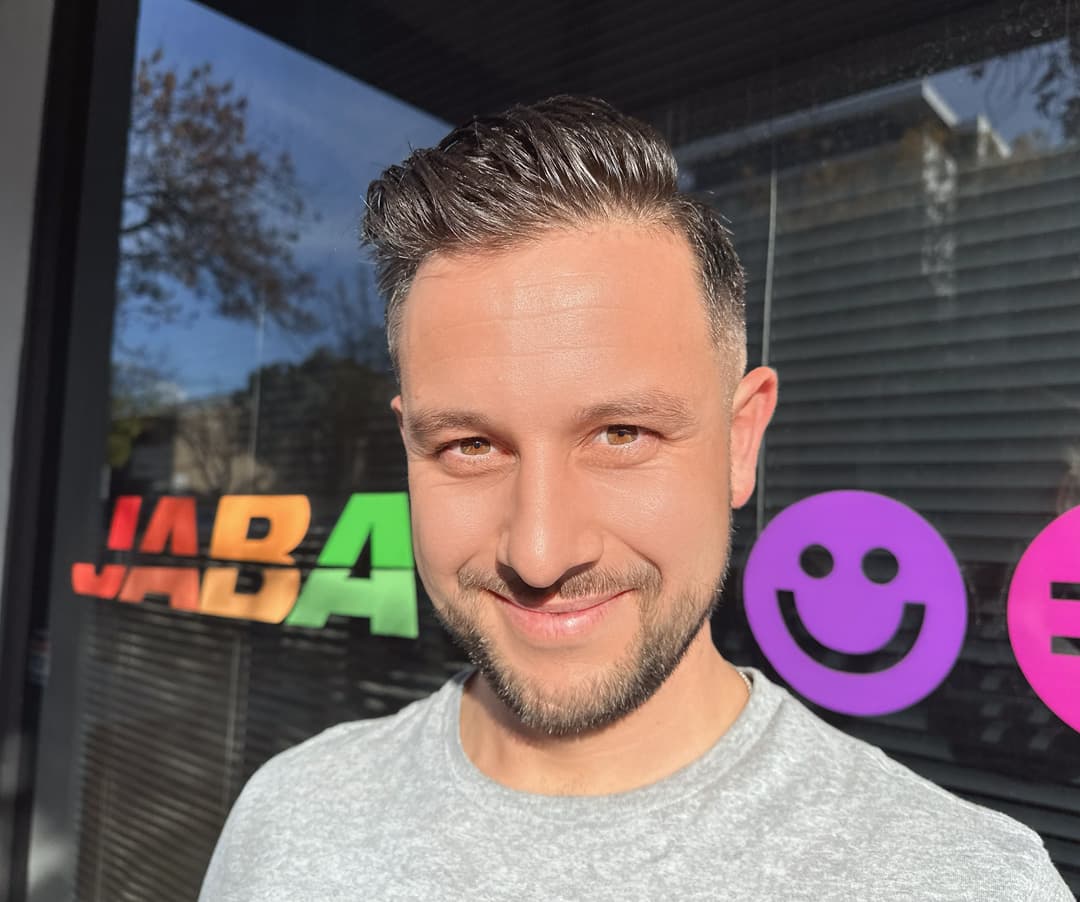 Jai, JABA team member, headshot in front of the JABA office signage