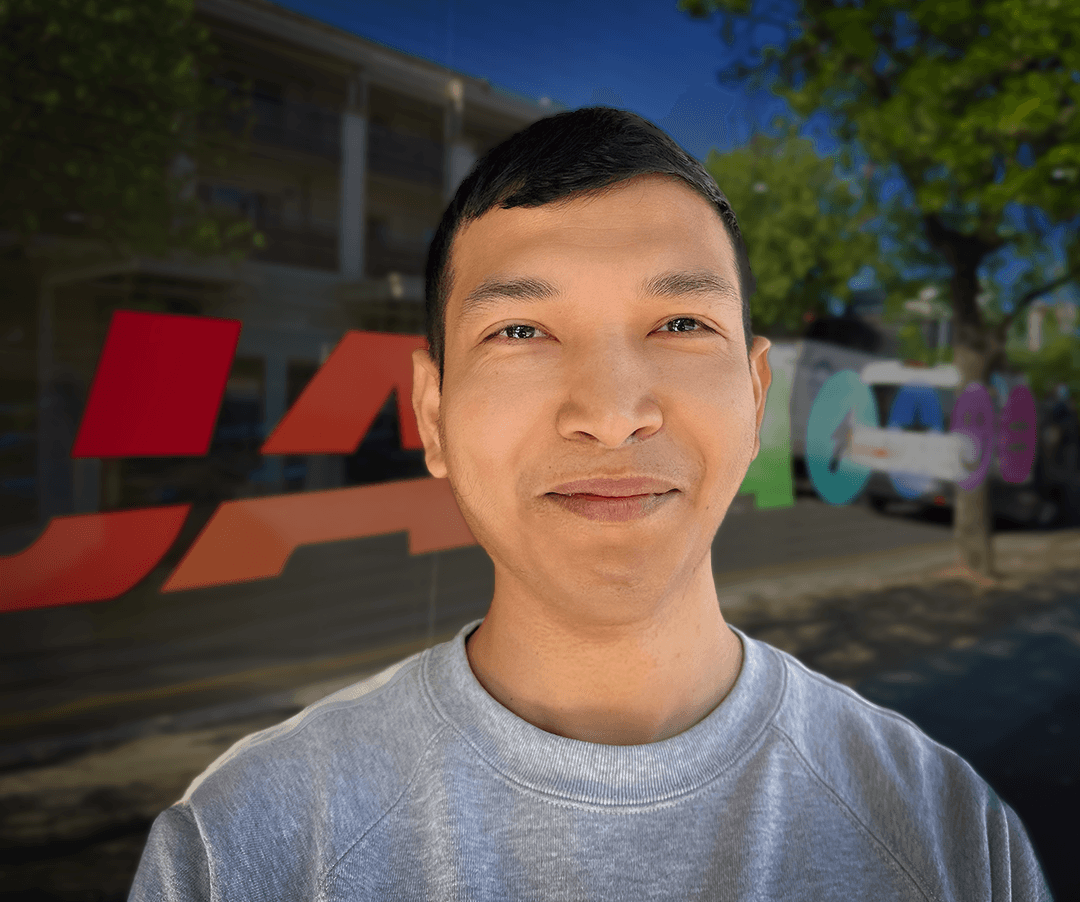 Suren, JABA team member, headshot in front of a JABA vehicle and office signage