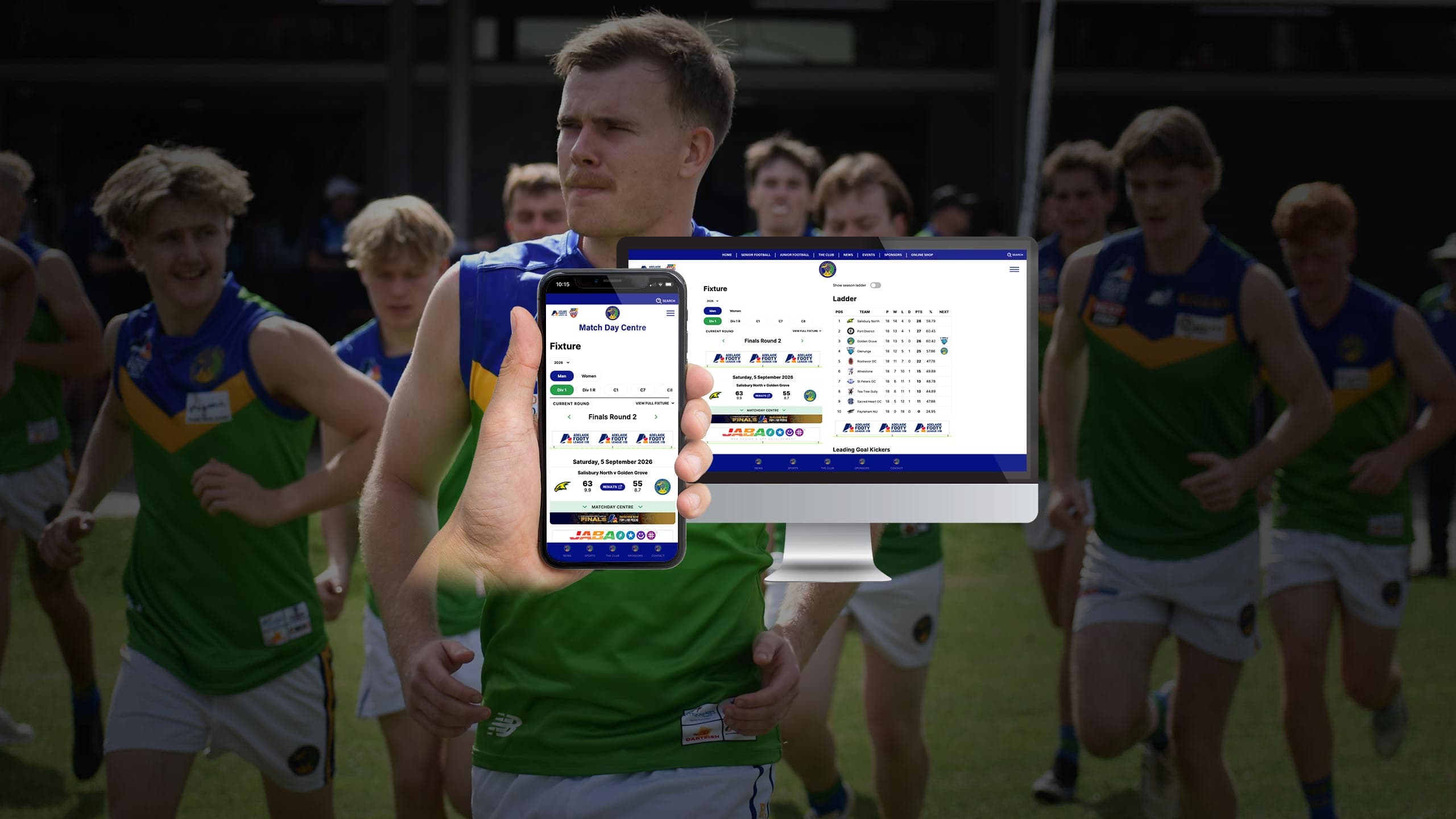 Golden Grove Football Club players running onto the field behind a monitor and phone showing the Match Day Centre fixture and ladder