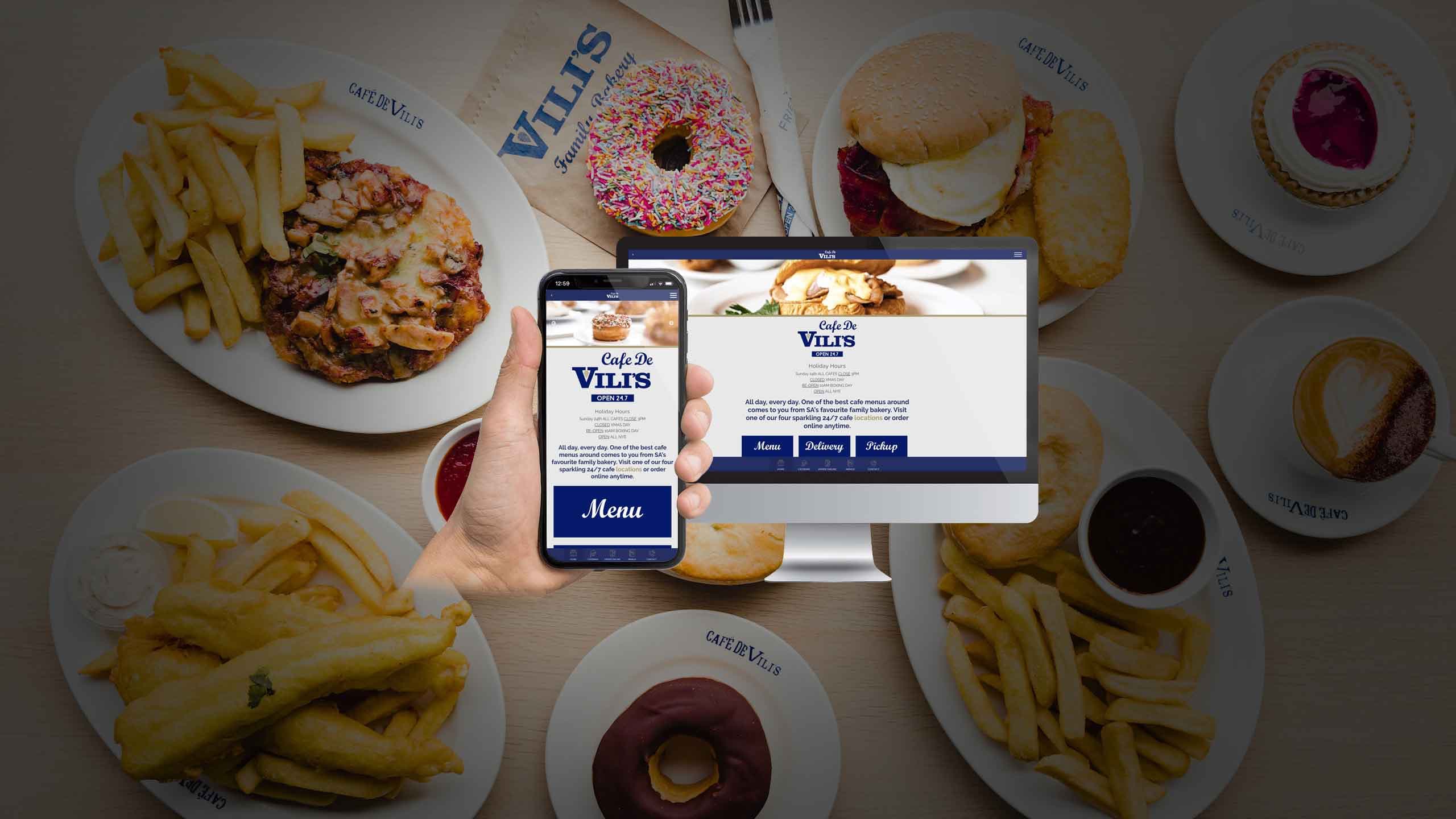 Cafe De Vili's website homepage displayed on a desktop monitor and smartphone over a spread of cafe food