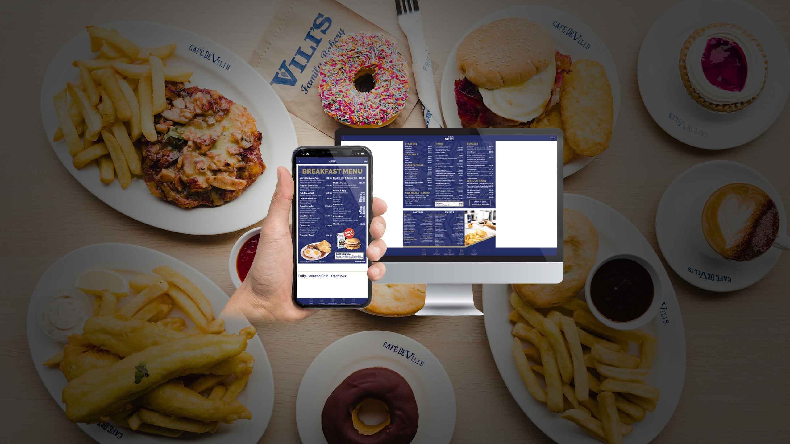Cafe De Vili's Breakfast Menu page displayed on a desktop monitor and smartphone over a spread of cafe food