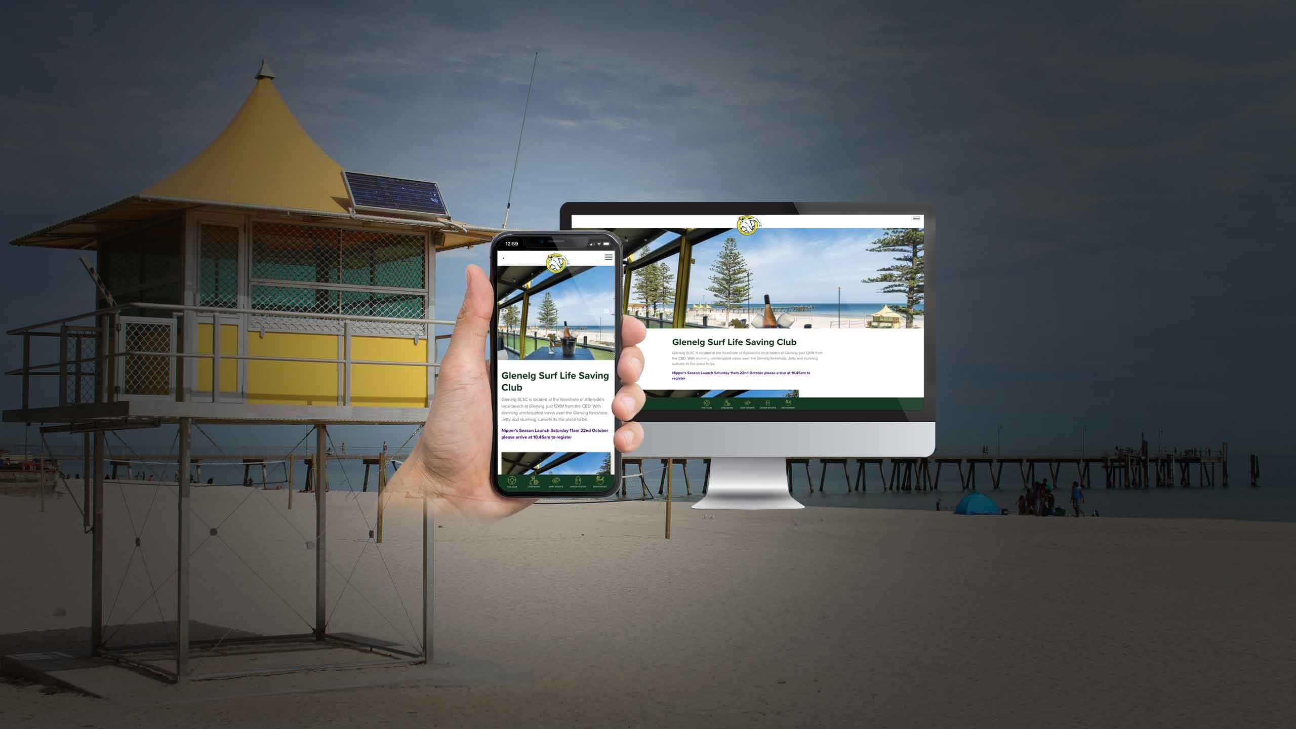 Glenelg lifeguard tower on the beach with the Glenelg Surf Life Saving Club website shown on a smartphone and monitor