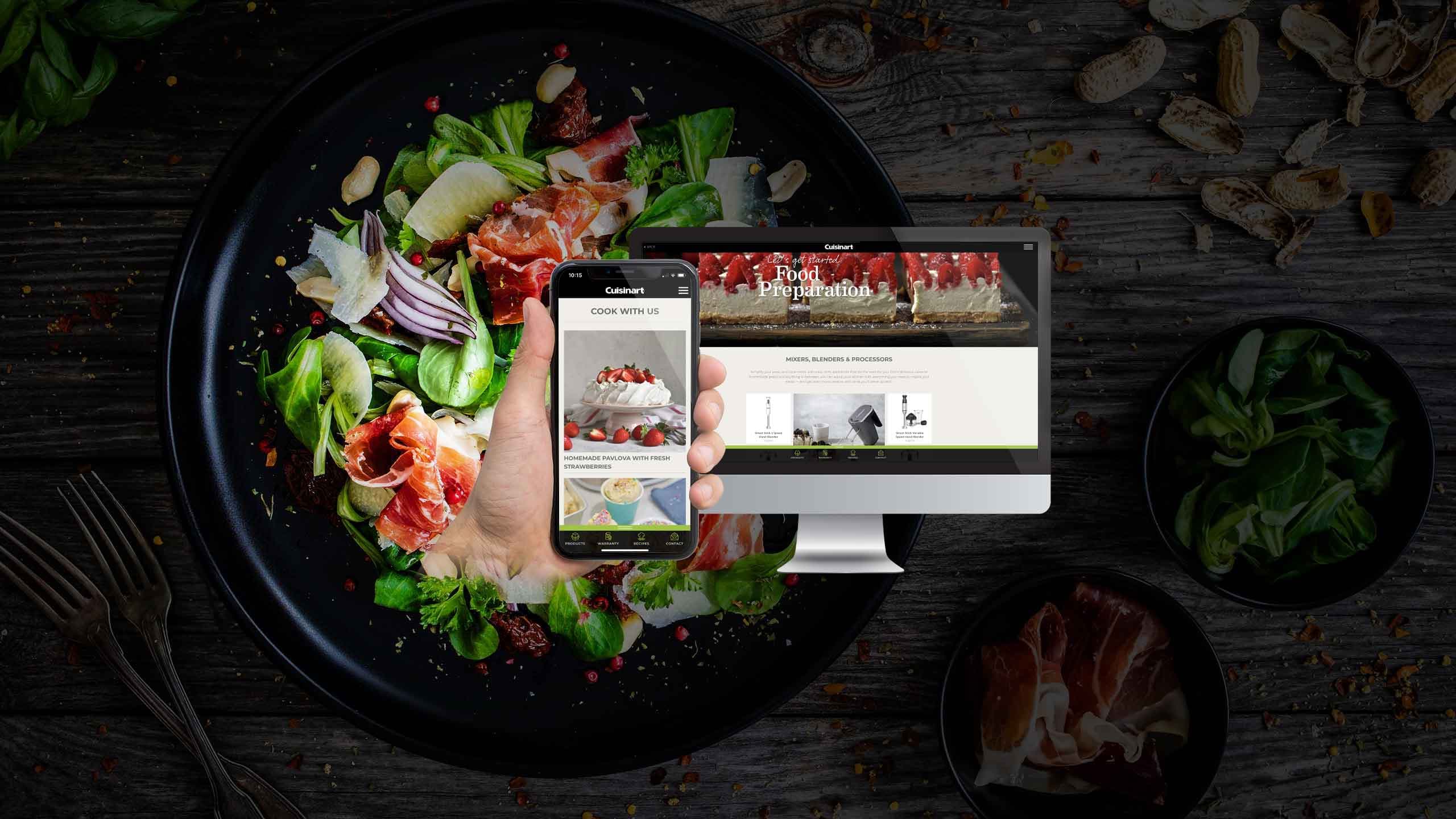 Cuisinart website food preparation page displayed on a desktop monitor and smartphone over a gourmet salad plate