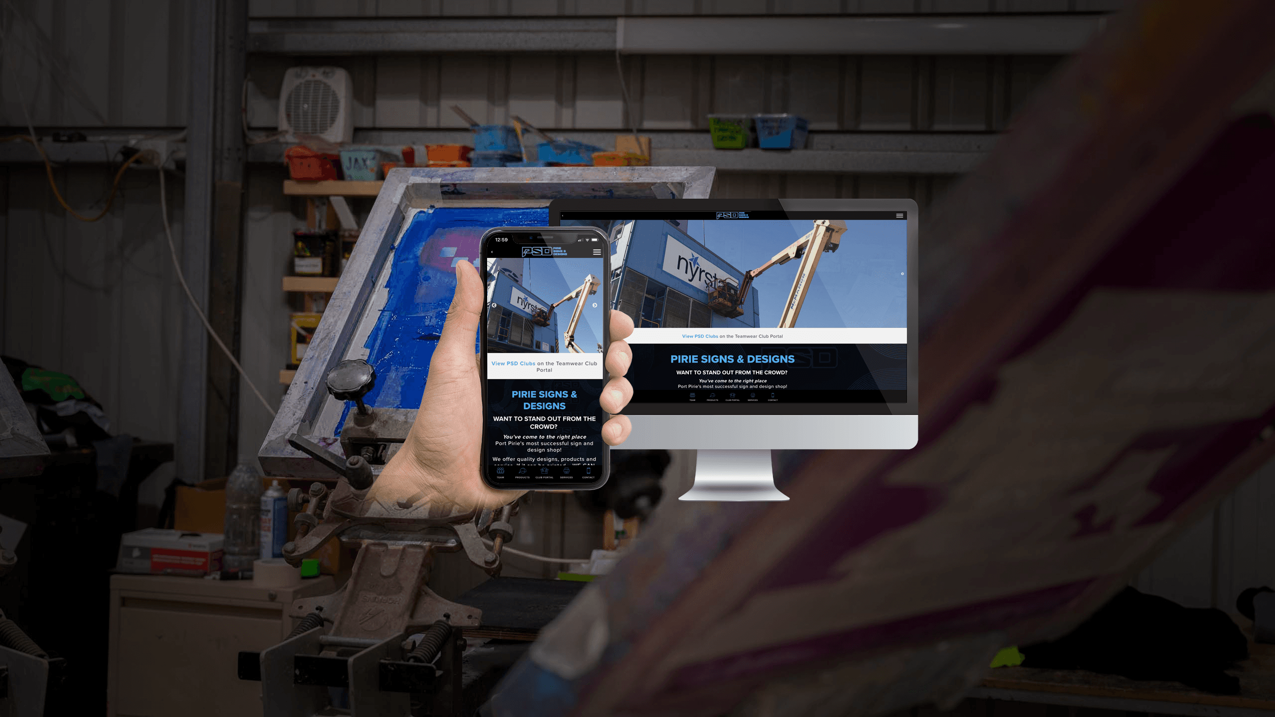 Pirie Signs & Designs website displayed on a desktop monitor and smartphone in a screen-printing workshop