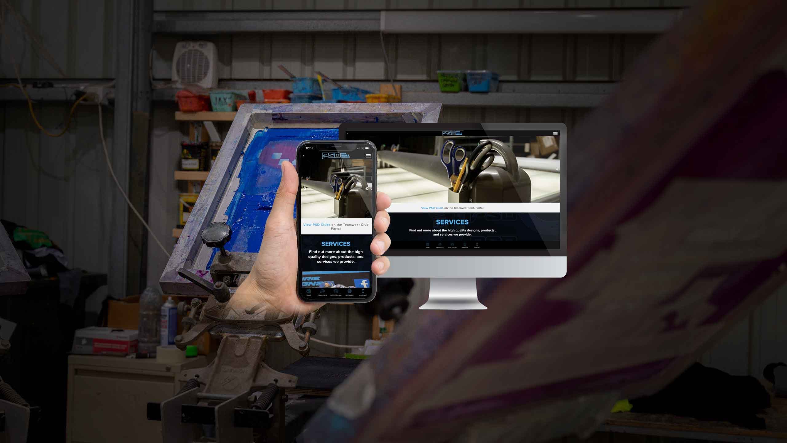 Pirie Signs & Designs Services page displayed on a desktop monitor and smartphone in a screen-printing workshop